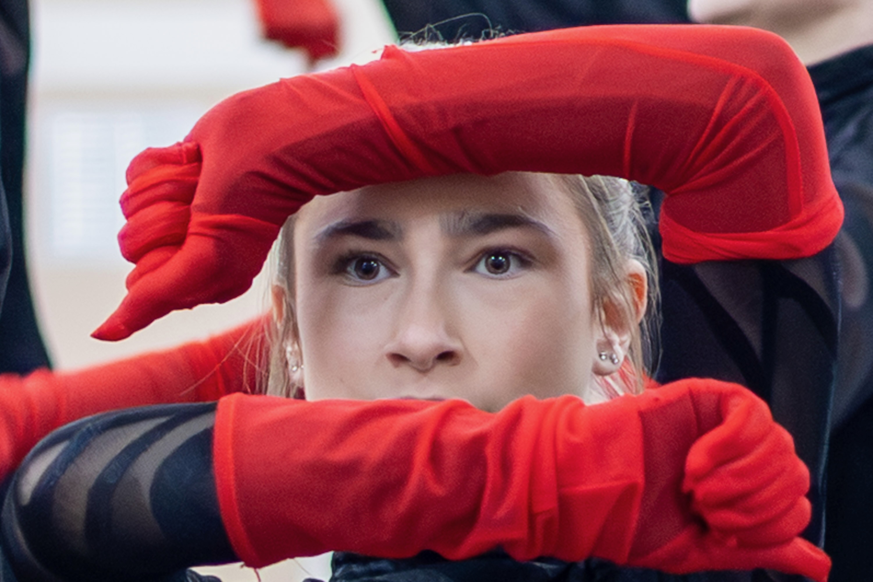 Close-up of dancer's eyes through red gloves